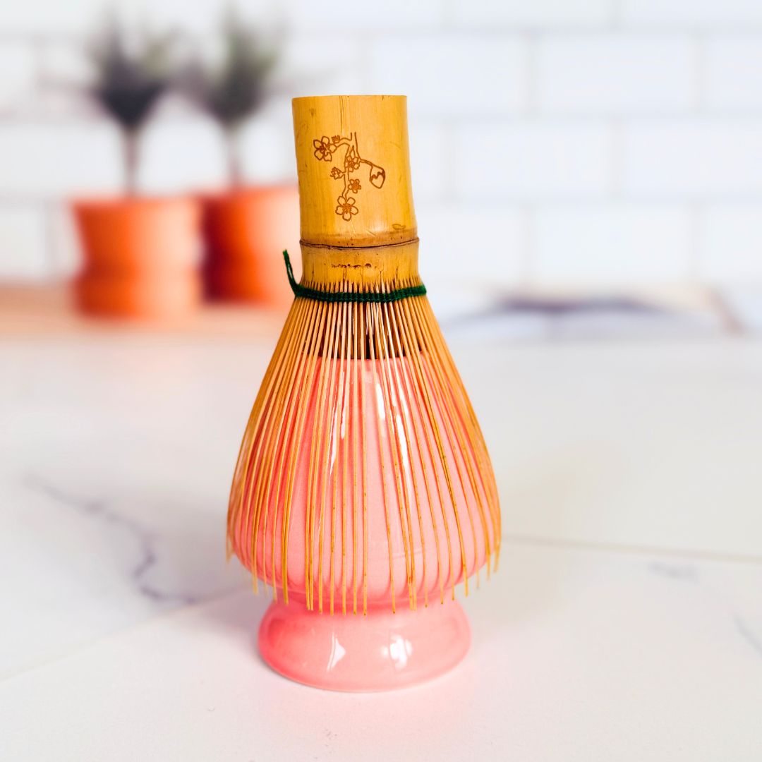 Bamboo whisk with pink base on a white surface