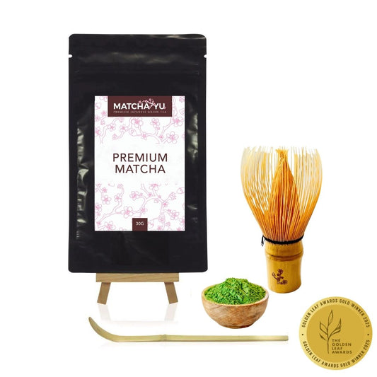 Matcha package with whisk, bowl of matcha powder, and award badge on a white background