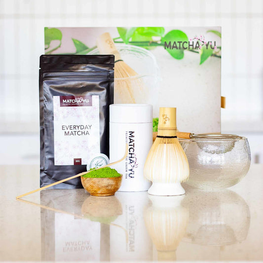 Matcha Yu tea products including a package, container, whisk, and bowl on a light surface.