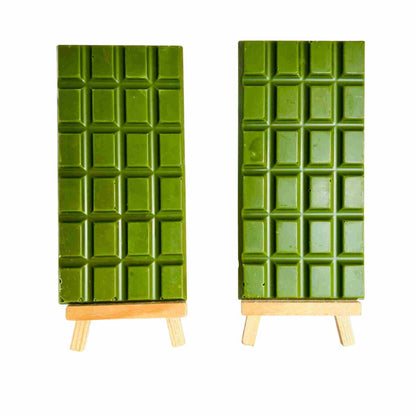 Two green chocolate bars on wooden stands against a white background