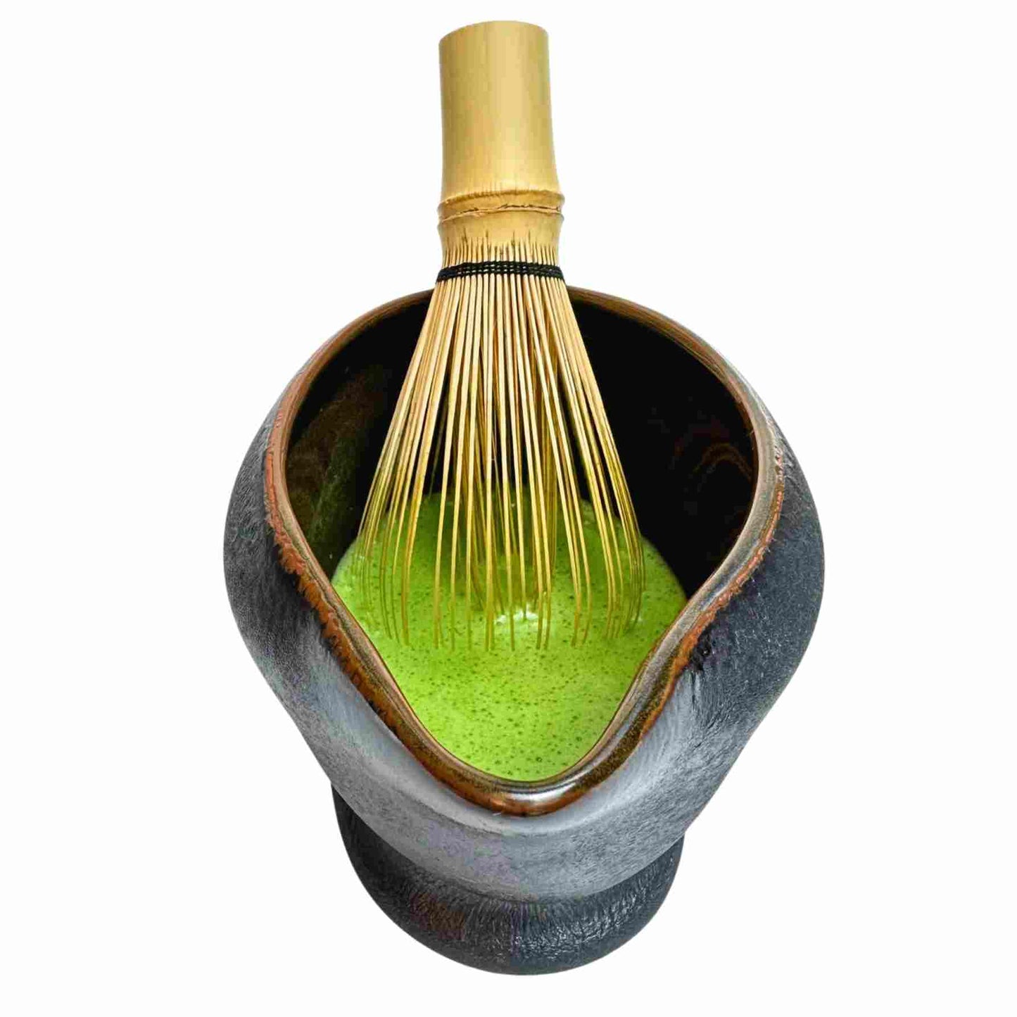 Ceramic bowl with green powder and a whisk on a white background