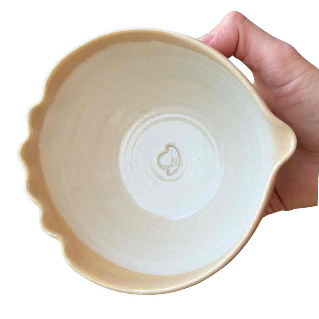 Hand holding a beige ceramic bowl against a white background