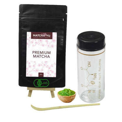Matcha Yu premium matcha packaging with a plastic container, wooden bowl, and bamboo whisk on a white background.