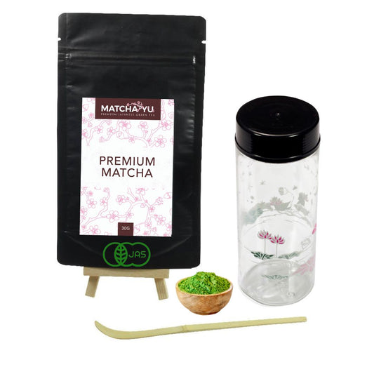 Matcha Yu premium matcha packaging with a small bowl of matcha powder, plastic shaker and scoop on a white background.