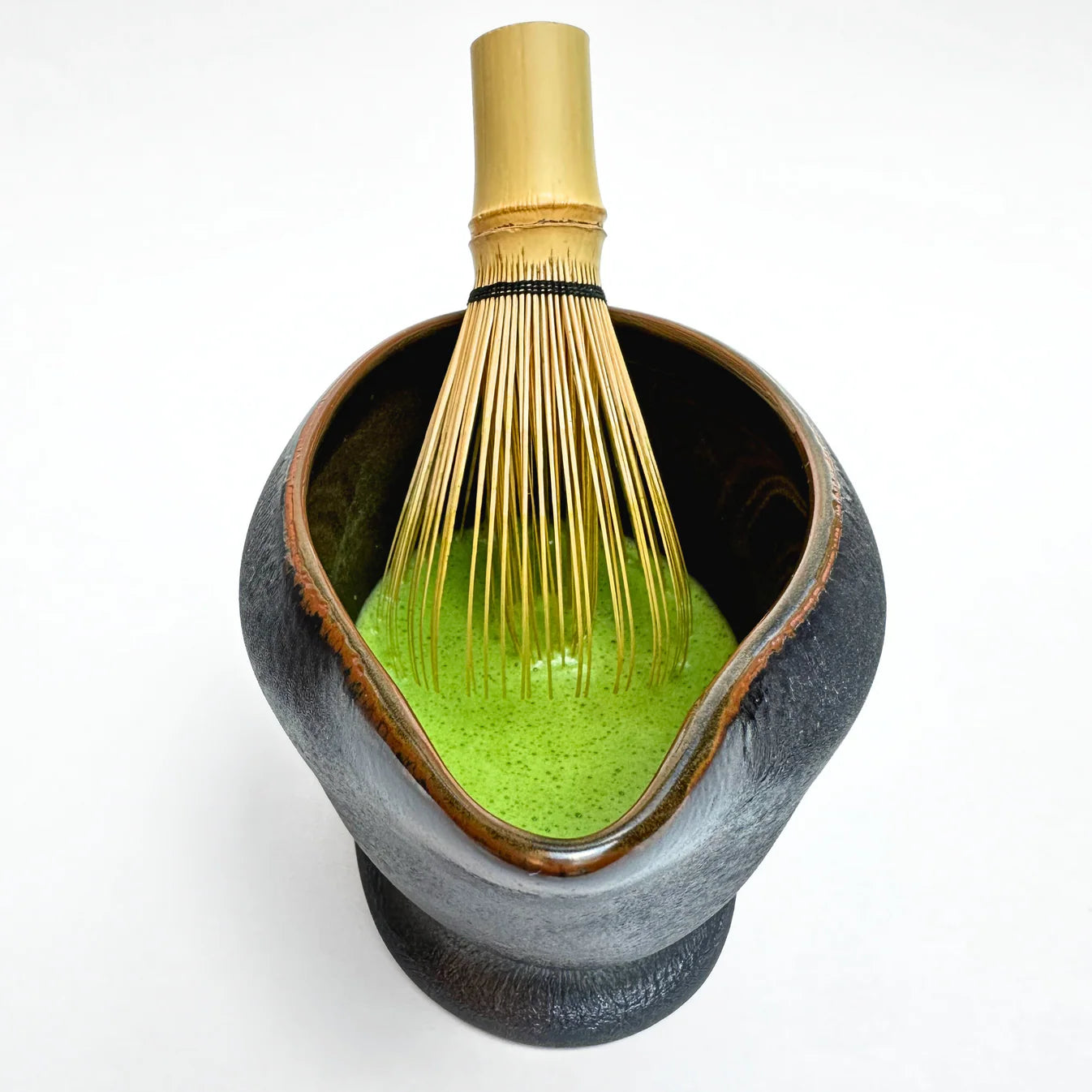 Ceramic Matcha bowl with green powder and a whisk on a white background